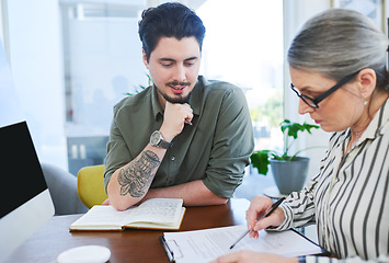 Image showing Running through some new ideas they had. two businesspeople going through paperwork together in an office.