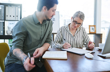 Image showing Planning everything to perfection. two businesspeople going through paperwork together in an office.