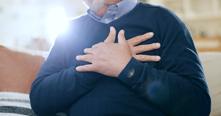 Image showing Hands, chest and heart attack with a senior man closeup on a sofa in the living room of his home during retirement. Healthcare, medical and cardiac arrest with an elderly person in pain or agony