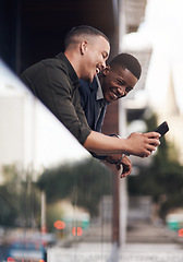 Image showing Taking a break to share a connection. two businessman looking at something on a cellphone while standing on the balcony of an office.