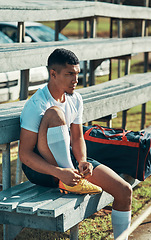 Image showing Getting ready to give his best on the field. a rugby player tying his shoelaces while sitting on a bench.