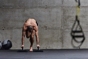 Image showing A muscular man in a handstand position, showcasing his exceptional balance and body control while performing a variety of exercises to enhance his overall body stability and strength in a modern gym