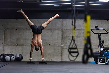 Image showing A muscular man in a handstand position, showcasing his exceptional balance and body control while performing a variety of exercises to enhance his overall body stability and strength in a modern gym