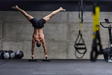 Image showing A muscular man in a handstand position, showcasing his exceptional balance and body control while performing a variety of exercises to enhance his overall body stability and strength in a modern gym