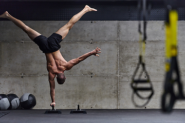 Image showing A muscular man in a handstand position, showcasing his exceptional balance and body control while performing a variety of exercises to enhance his overall body stability and strength in a modern gym