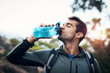 Image showing Nothing like the freshness of water. a carefree young man drinking water from a bottle while going for a hike up a mountain.