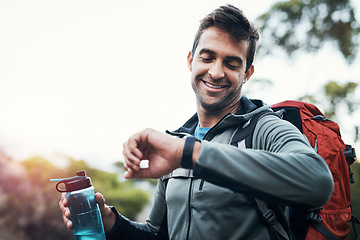 Image showing I better keep moving. a cheerful young man looking at his watch while going for a hike up a mountain.