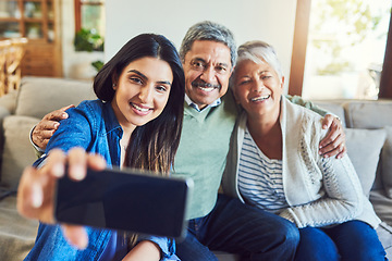 Image showing Capturing every special moment. a cheerful senior couple and their daughter taking a selfie together while sitting on a couch at home.