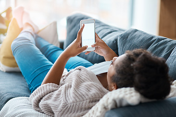 Image showing Let me reply to a few texts. Full length shot of an unrecognizable woman using her smartphone while lying on the sofa.