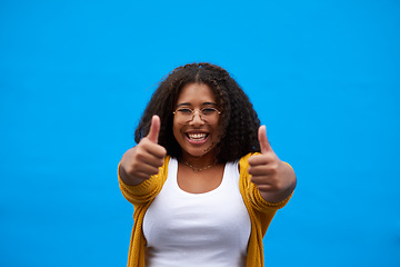 Image showing Youve got it right. Cropped portrait of an attractive young woman showing thumbs up against a blue background.