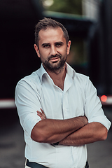 Image showing A successful businessman in a white shirt, with crossed arms, poses outdoors, confident expression on his face.