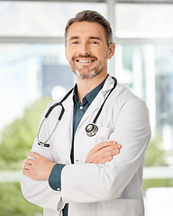 Image showing Caring for you is simply what we do. a medical practitioner standing with his arms crossed in a hospital.