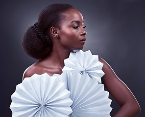 Image showing The most attractive people are those that allow their light to shine. Studio shot of a beautiful young woman posing with origami fans against a black background.