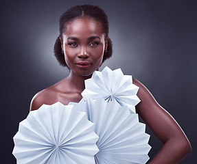 Image showing The world needs your light, so keep shining. Studio portrait of a beautiful young woman posing with origami fans against a black background.