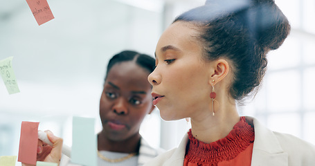 Image showing Sticky note, glass wall and business people writing, collaboration or brainstorming creative strategy, notes or ideas. Problem solving, teamwork and professional women planning advertising project