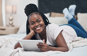 Image showing My social network is keeping me company today. a young woman using a digital tablet while relaxing on her bed at home.