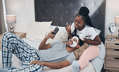 Image showing You can stay home and still keep your glow. a young couple taking selfies while getting homemade facials together at home.