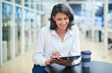 Image showing Working through her to dos one tap at a time. a young businesswoman using a digital tablet during a coffee break in a modern office.