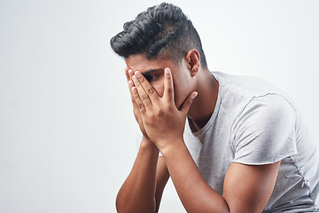 Image showing Im not sure how to feel. Studio shot of a young man sitting against a white background.