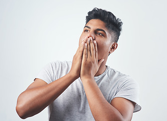 Image showing Its just too good to be true. Studio shot of a young man sitting against a white background.