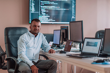 Image showing A programmer diligently testing smartphone applications while sitting in their office.