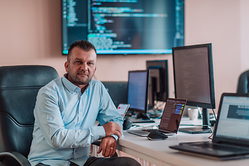 Image showing A programmer diligently testing smartphone applications while sitting in their office.