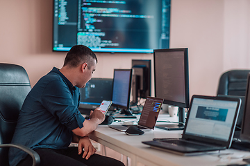 Image showing A programmer diligently testing smartphone applications while sitting in their office.