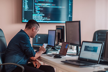 Image showing A programmer diligently testing smartphone applications while sitting in their office.