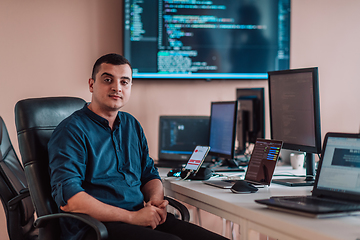 Image showing A programmer diligently testing smartphone applications while sitting in their office.