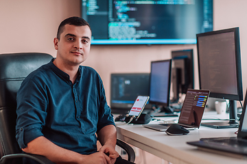 Image showing A programmer diligently testing smartphone applications while sitting in their office.