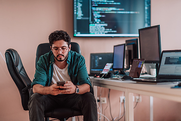 Image showing A programmer diligently testing smartphone applications while sitting in their office.