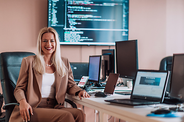 Image showing A businesswoman sitting in a programmer's office surrounded by computers, showing her expertise and dedication to technology.