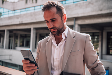 Image showing A businessman using his smartphone outdoors, showcasing the seamless integration of technology and mobility in modern professional life.