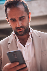 Image showing A businessman using his smartphone outdoors, showcasing the seamless integration of technology and mobility in modern professional life.