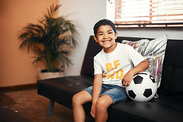 Image showing Soccer is so much fun. Portrait of an adorable little boy sitting with a soccer ball on the sofa at home.