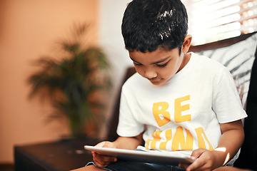 Image showing Becoming curious about the online world. an adorable little boy using a digital tablet on the sofa at home.