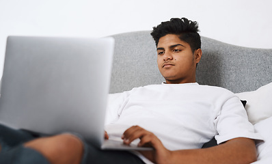 Image showing The internet is a plethora of entertainment. an young man using his laptop while lying on his bed.