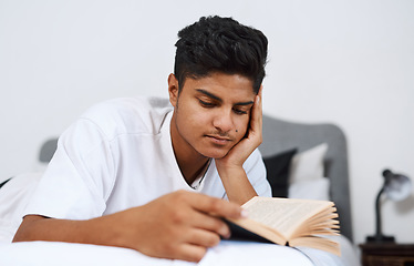 Image showing Ive been reading a lot lately. a young man reading a book while lying on his bed.