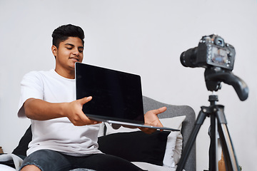 Image showing Use my code and youll get discount. a young man using a camera on a tripod to record himself at home.