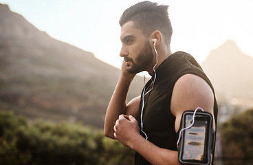 Image showing Plug in and get moving. a sporty young man listening to music while exercising outdoors.