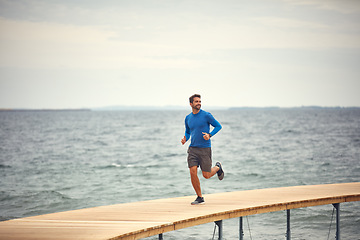 Image showing Start your day with a good run. a sporty middle-aged man out running by the seaside.