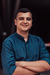 Image showing A successful young businessman in a shirt, with crossed arms, poses outdoors, confident expression on his face.