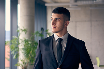 Image showing A confident businessman with a briefcase strides through a modern office, exuding charisma and determination, symbolizing success and professional excellence.