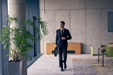 Image showing A confident businessman with a briefcase strides through a modern office, exuding charisma and determination, symbolizing success and professional excellence.