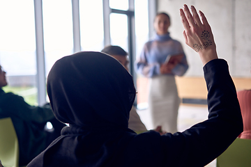 Image showing A young hijab woman entrepreneur is attentively listening to a presentation by her colleagues, reflecting the spirit of creativity, collaboration, problem-solving, entrepreneurship, and empowerment.