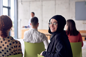 Image showing A young hijab woman entrepreneur is attentively listening to a presentation by her colleagues, reflecting the spirit of creativity, collaboration, problem-solving, entrepreneurship, and empowerment.