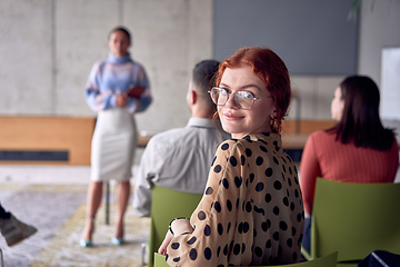 Image showing A young female entrepreneur is attentively listening to a presentation by her colleagues, reflecting the spirit of creativity, collaboration, problem-solving, entrepreneurship, and empowerment.