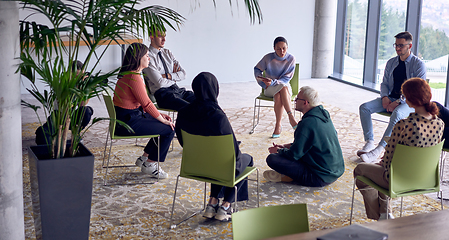 Image showing A man sitting at the center of a circle, passionately sharing his business ideas with his colleagues, fostering an atmosphere of collaboration and innovation in a dynamic and engaging workplace.