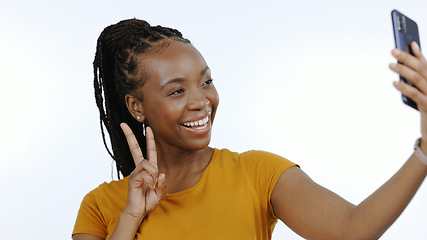 Image showing Black woman, peace sign and selfie for social media, influencer content creation or blog in studio. Happy young person with smile and emoji for profile picture or photography on a white background