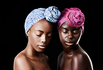 Image showing Gorgeously glowing. Studio shot of two beautiful women wearing headscarves against a black background.